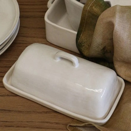 The Creamery Handcrafted Butter Dish has a unique organic shape, texture and colour, adding to the item's distinct beauty. The dish is composed of stoneware and boasts a soft ivory cream glaze, combining to create a timeless look. These pieces are designed to offer everyday convenience as they are dishwasher, microwave, and oven safe.