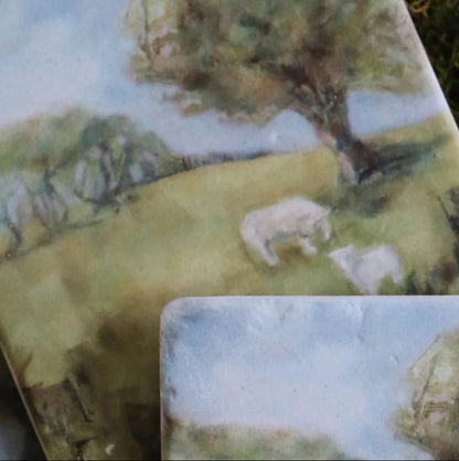 Two ceramic coasters with a scenic landscape design featuring trees and animals.