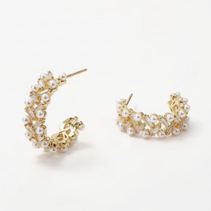 Pair of gold hoop earrings with pearl accents on a white background