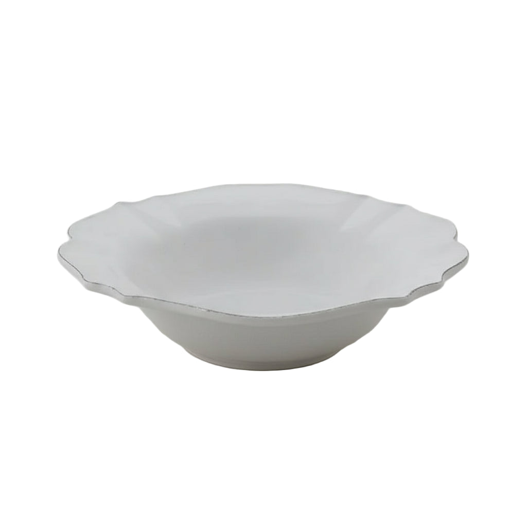 White ceramic bowl with scalloped edge on a light gray background