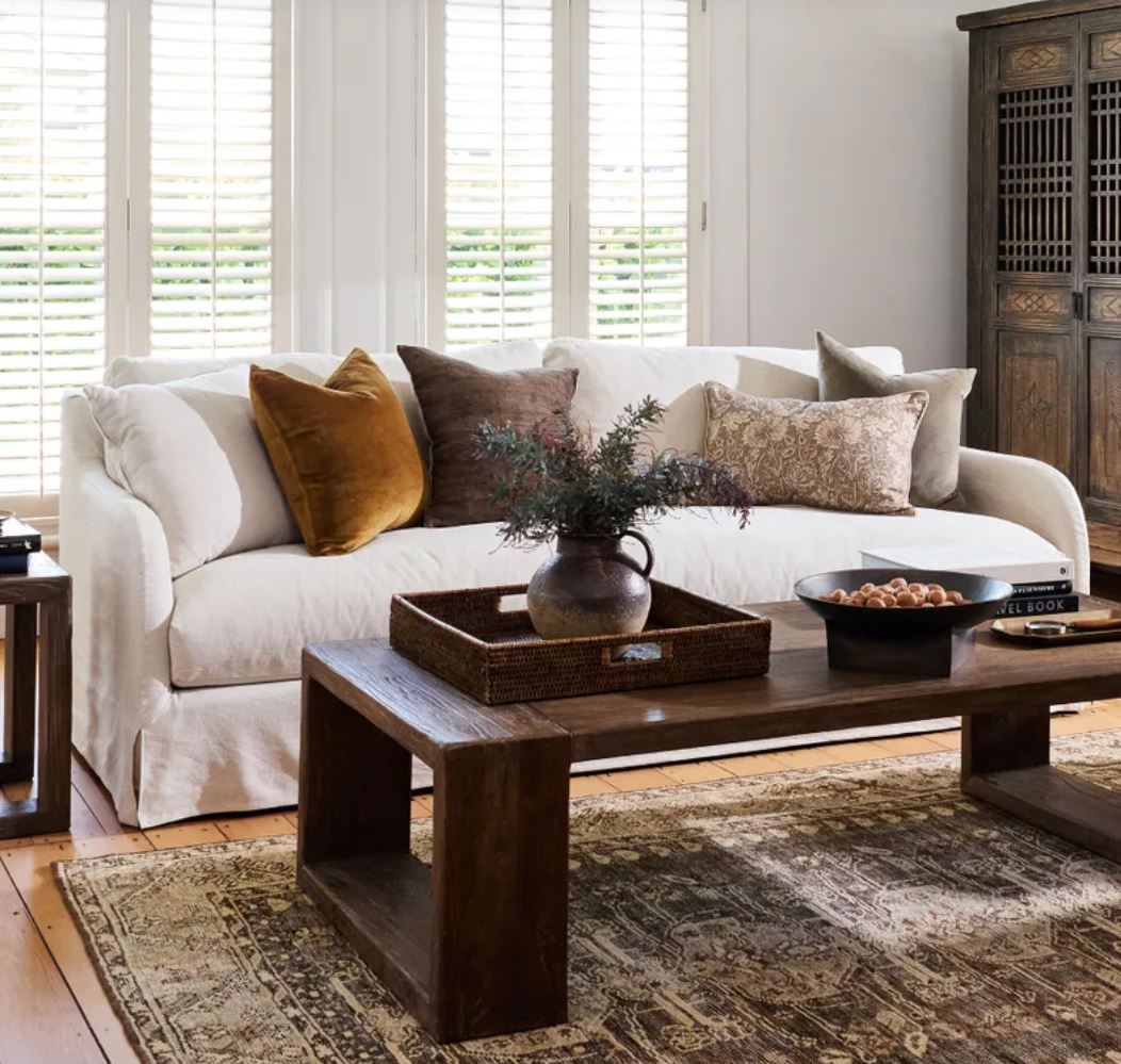 Living room with a white sofa, wooden coffee table, and decorative items.