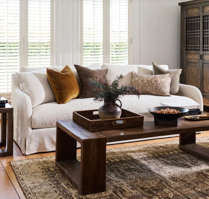 Living room with a white sofa, wooden coffee table, and decorative items.
