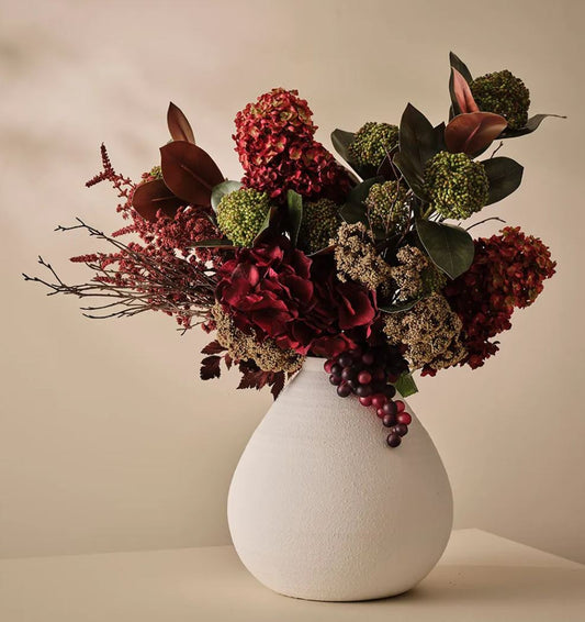 Bouquet of flowers in a white vase on a beige background