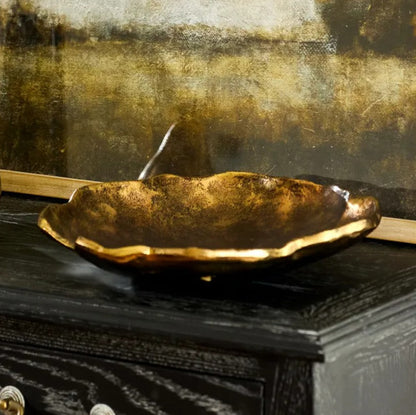 Decorative gold bowl on a dark surface with a textured background