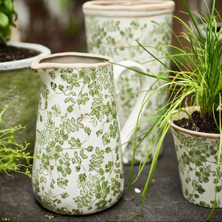 Ceramic planters with green floral patterns on a stone surface