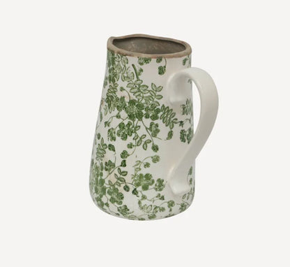 Ceramic pitcher with green floral pattern on a white background