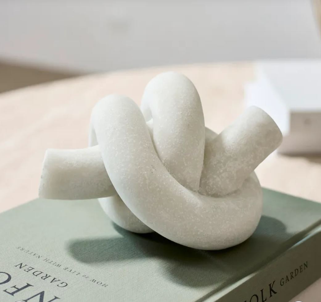 White knot-shaped object on a book with a blurred background