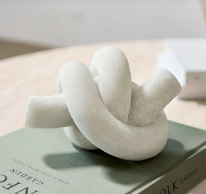 White knot-shaped object on a book with a blurred background