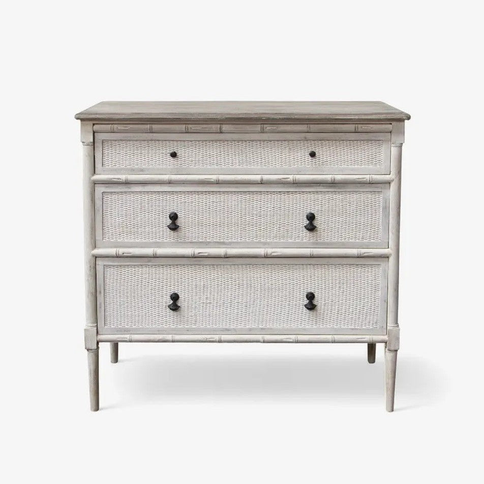 Three-drawer dresser with rattan design and black knobs on a white background