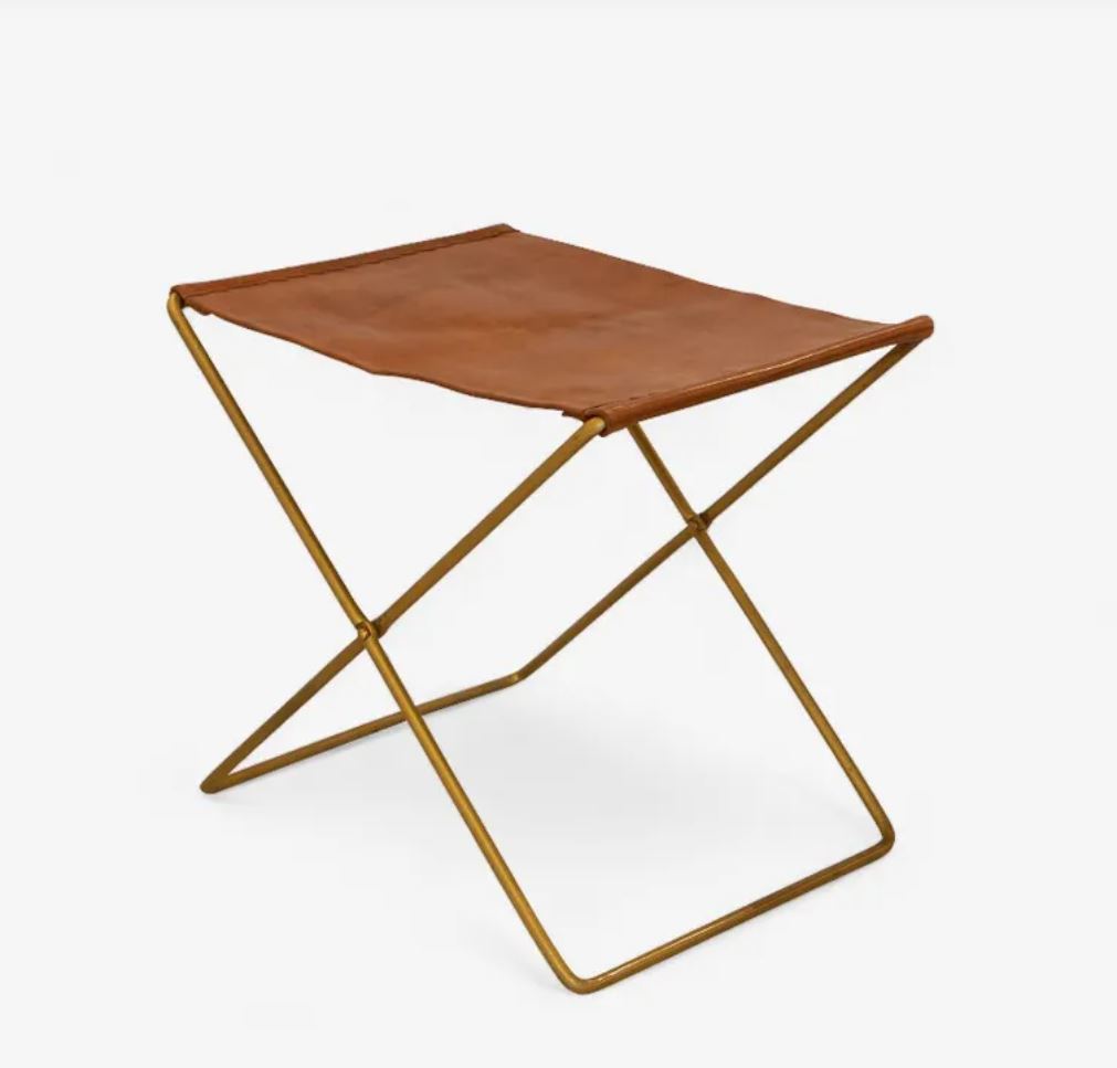 A folding stool with a brown leather seat and a gold metal frame, shown on a plain white background.