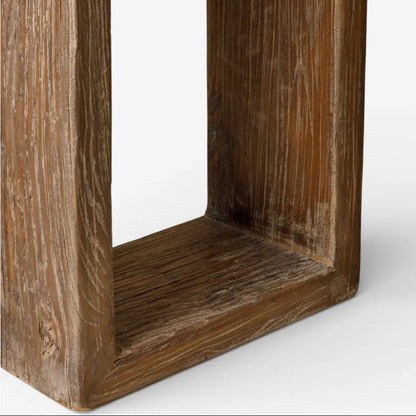 A close-up of a rustic wooden furniture frame, showing the corner joint and weathered grain of the brown wood on a light gray background.