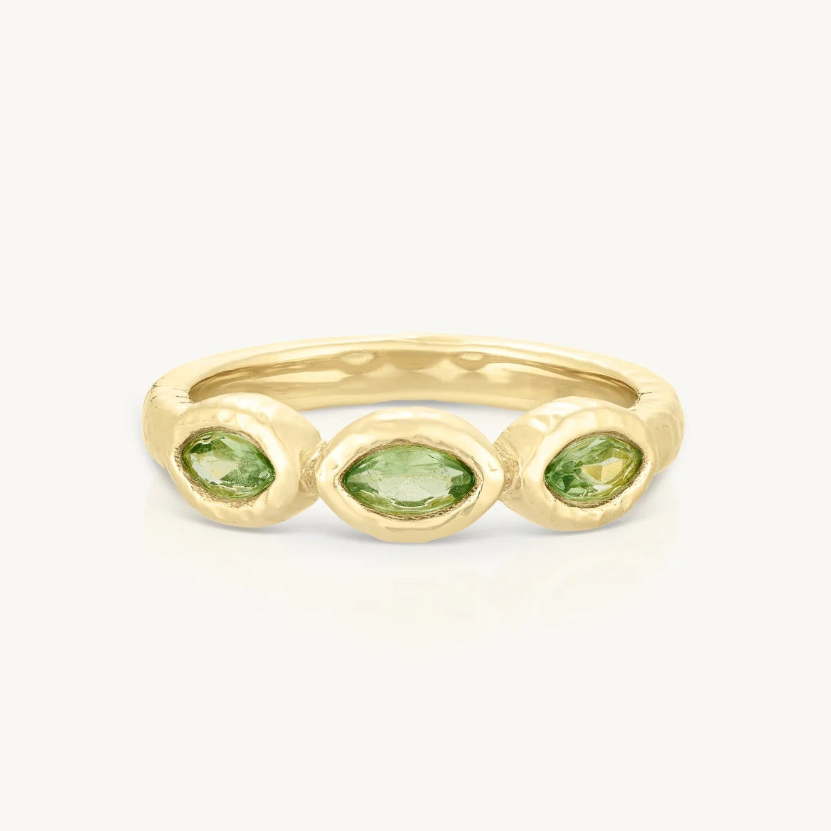 Gold ring with three green gemstones on a white background