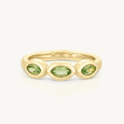 Gold ring with three green gemstones on a white background