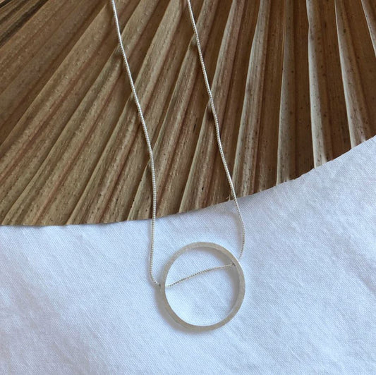 Necklace with a circular pendant on a wooden surface