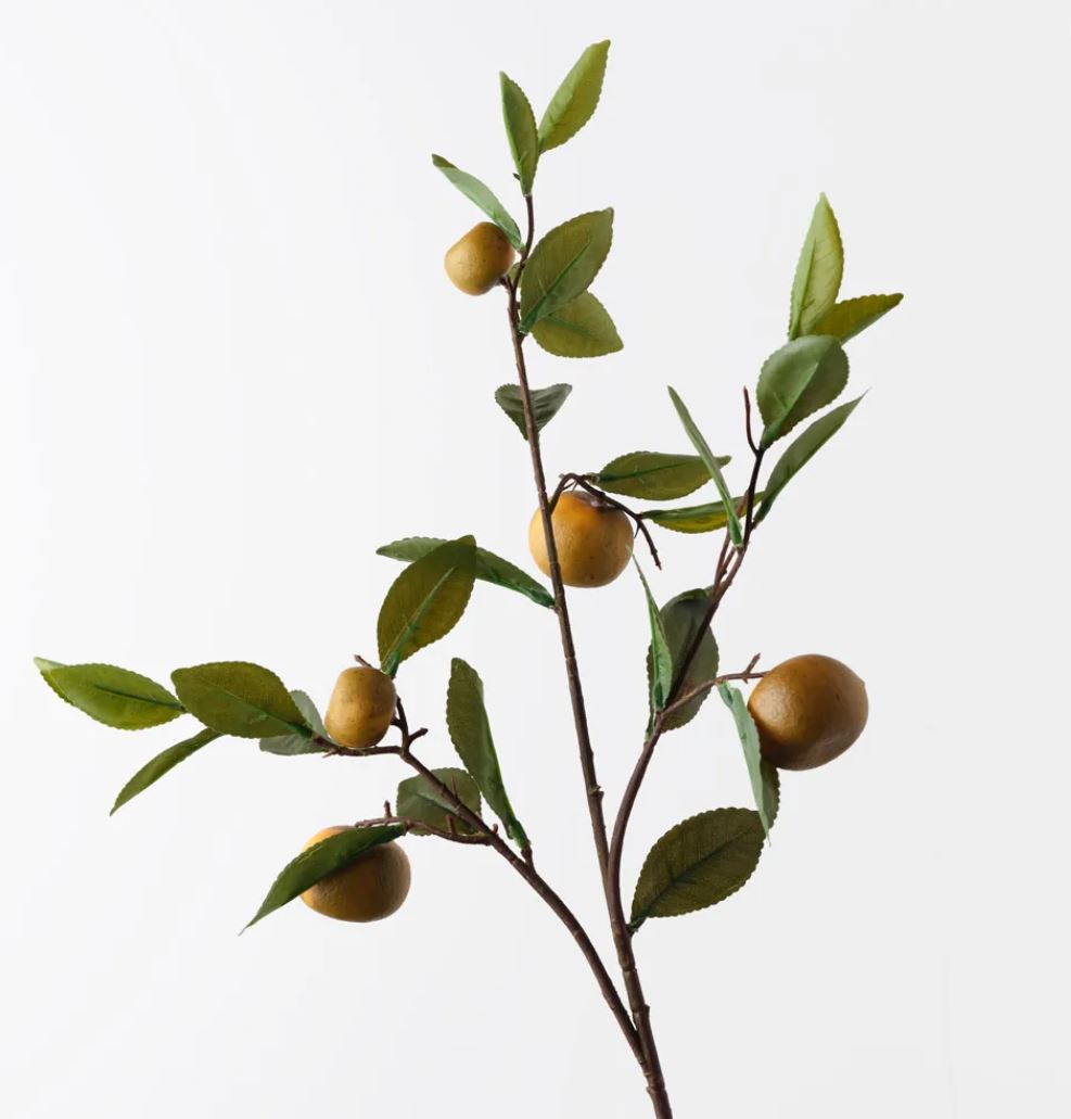 Artificial orange branch with green leaves and small yellow orange on a white background