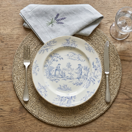 Table setting with a decorative plate, napkin, and glasses on a wooden table.