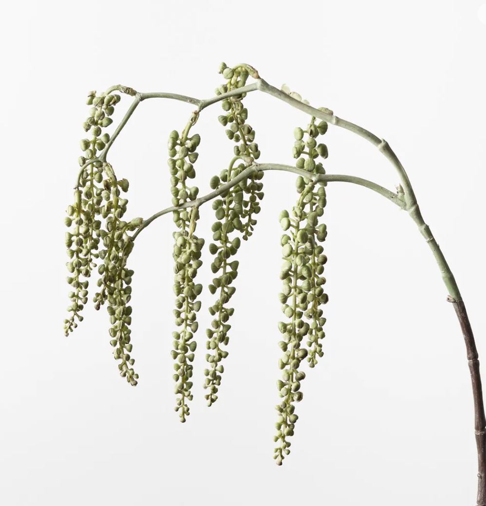 Artificial plant branch with hanging green leaves on a white background