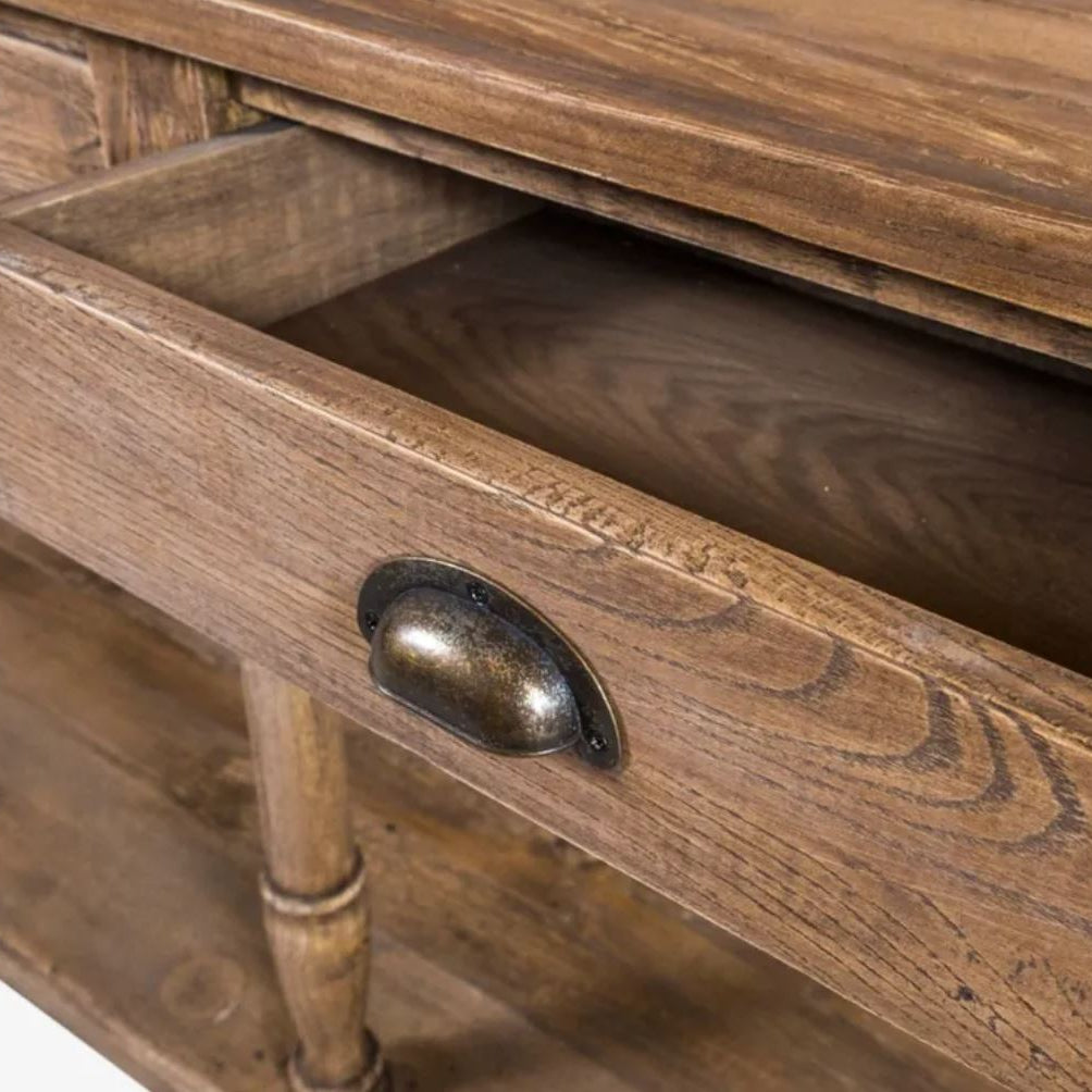 Close-up of a rustic wooden cabinet drawer with a dark metal oval pull handle, showing the wood grain and interior of the open drawer.