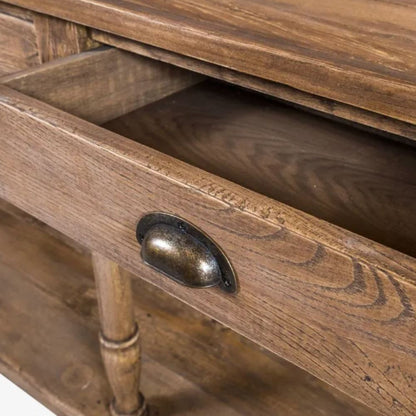 Close-up of a rustic wooden cabinet drawer with a dark metal oval pull handle, showing the wood grain and interior of the open drawer.