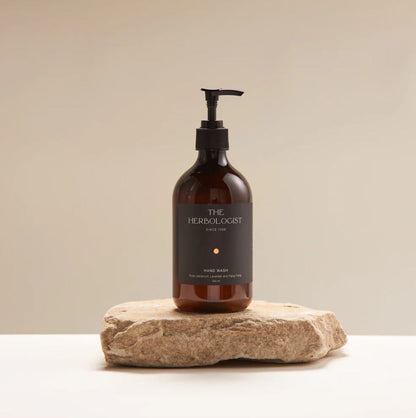 Brown bottle with pump labeled 'The Herbologist' on a beige background