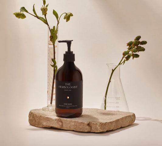 Bottle labeled 'The Herbologist' on a stone surface with flowers in the background