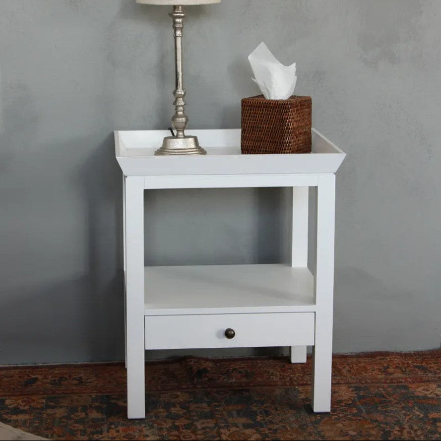 White nightstand with lamp and tissue box against a gray wall