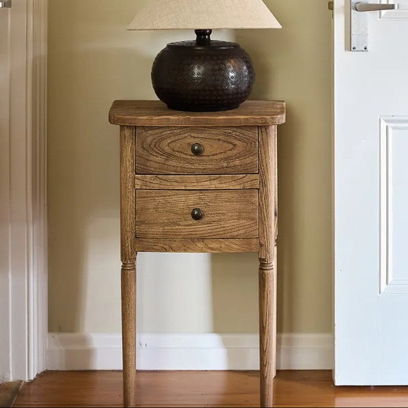 Wooden side table with a lamp against a neutral wall.