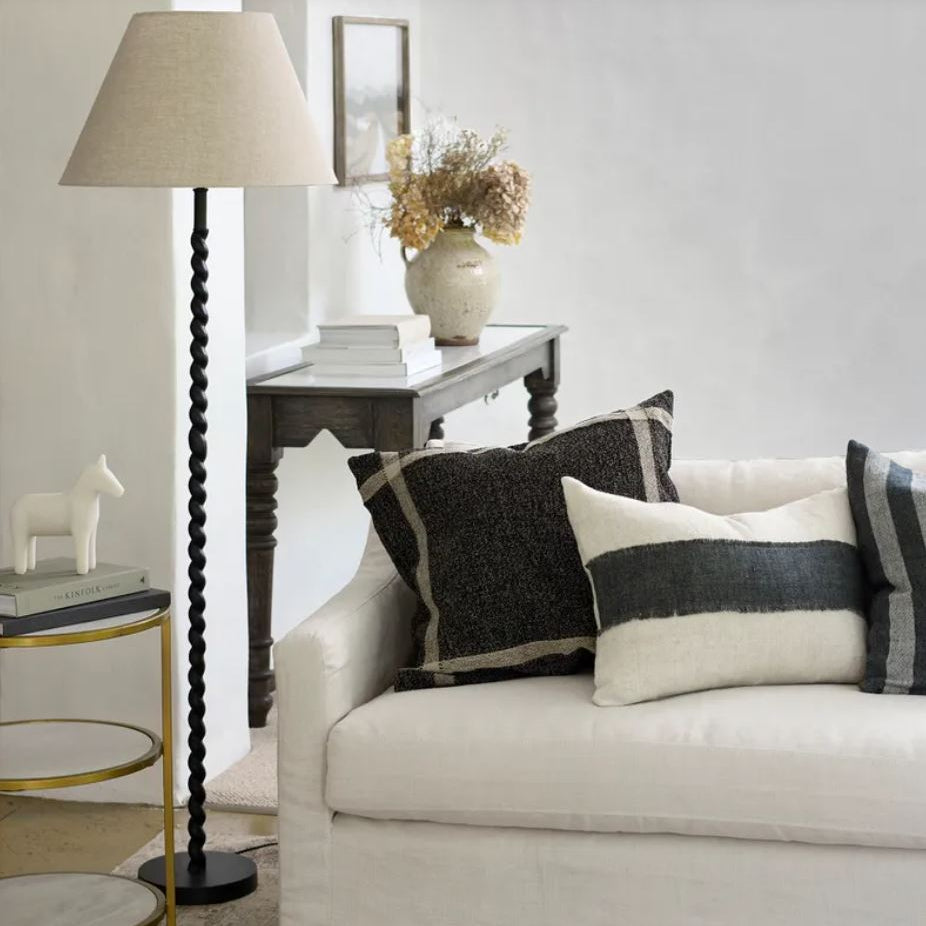 Living room with a white sofa, decorative pillows, and a lamp.