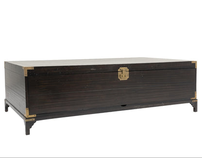 A dark brown wooden chest with brass corner guards and a central latch, shown from a three-quarter angle on a white background.
