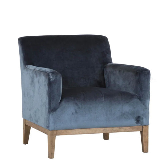 The Chantelle Velvet Armchair boasts a timeless design, featuring a solid timber frame wrapped in a sumptuous deep blue grey velvet for added allure.
