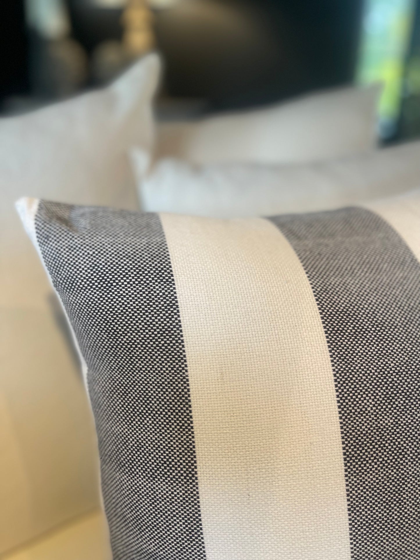 Our Lyon Handwoven Cotton Cushion boasts sleek stripes and provides versatile styling, ideal for complementing sofas and beds. Its luxurious Dacron insert adds additional comfort. Black and white coloured. Close up corner.