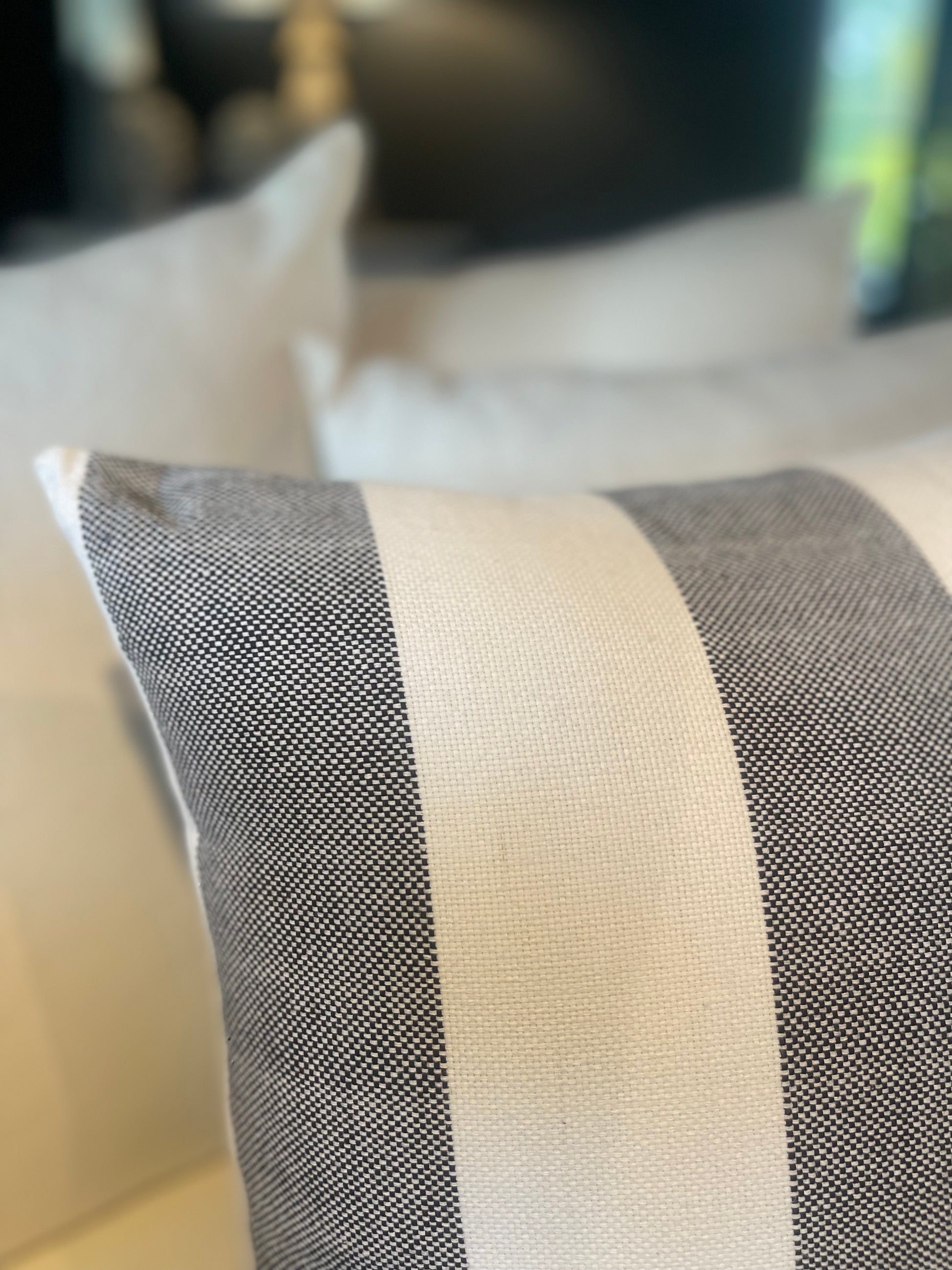 Our Lyon Handwoven Cotton Cushion boasts sleek stripes and provides versatile styling, ideal for complementing sofas and beds. Its luxurious Dacron insert adds additional comfort. Black and white coloured. Close up corner.