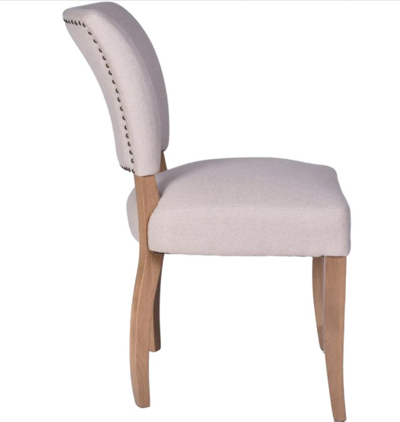 The Chelsea Dining Chair is constructed with a cream linen finish and features stud detailing on the back for a sophisticated, yet comfortable aesthetic. Side