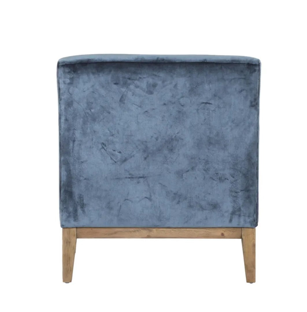 The Chantelle Velvet Armchair boasts a timeless design, featuring a solid timber frame wrapped in a sumptuous deep blue grey velvet for added allure.