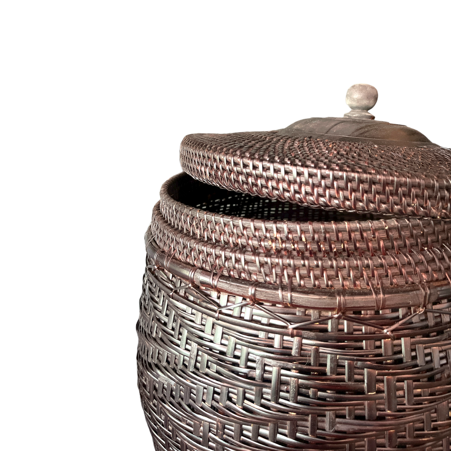 Crafted by skilled artisans from East Indonesian Island Villages using locally-sourced rattan and bamboo, the Cahyono Handmade Rattan & Bamboo Basket is visually stunning and exceptionally functional. Their deep, rich brown and black colour is complemented by a sturdy lid and wooden handle, making them the perfect choice for decorative accents or convenient storage solutions. Close up.
